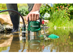 Man using a green PARKSIDE submersible pump for clear/dirty water in a pond.