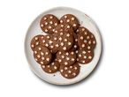 Round chocolate cookies with white star sprinkles on a rustic plate.
