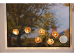 Halloweeni kõrvitsatega valgusketid, rippumas aknas vaatega puudele.