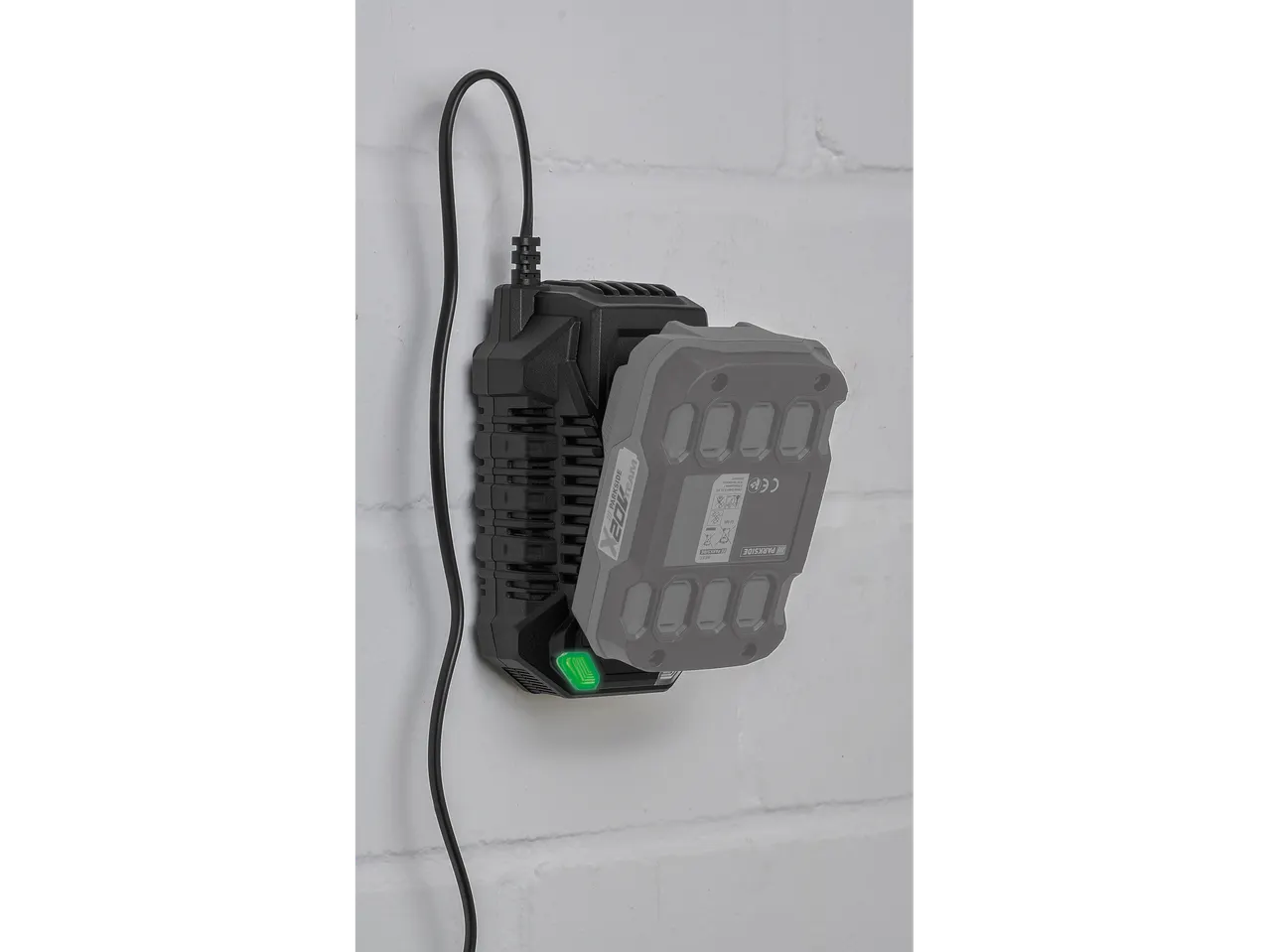Încărcător de baterii Parkside® cu baterie conectată pe un perete alb.