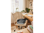 A black and gray memory foam seat cushion sits on a beige office chair in a sunlit home office.