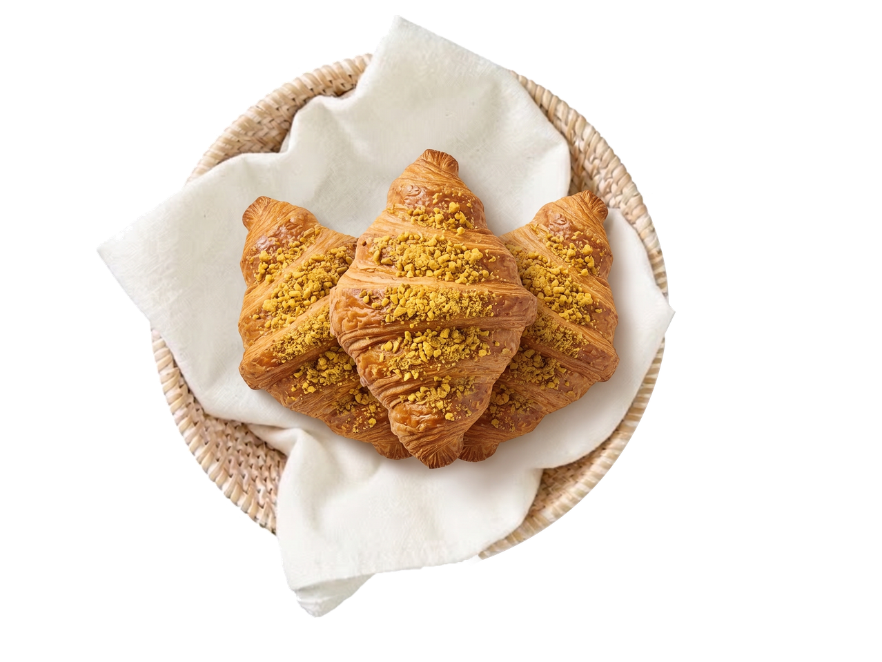 Drie croissants met pistachenootjes in een rieten mand met een witte doek.