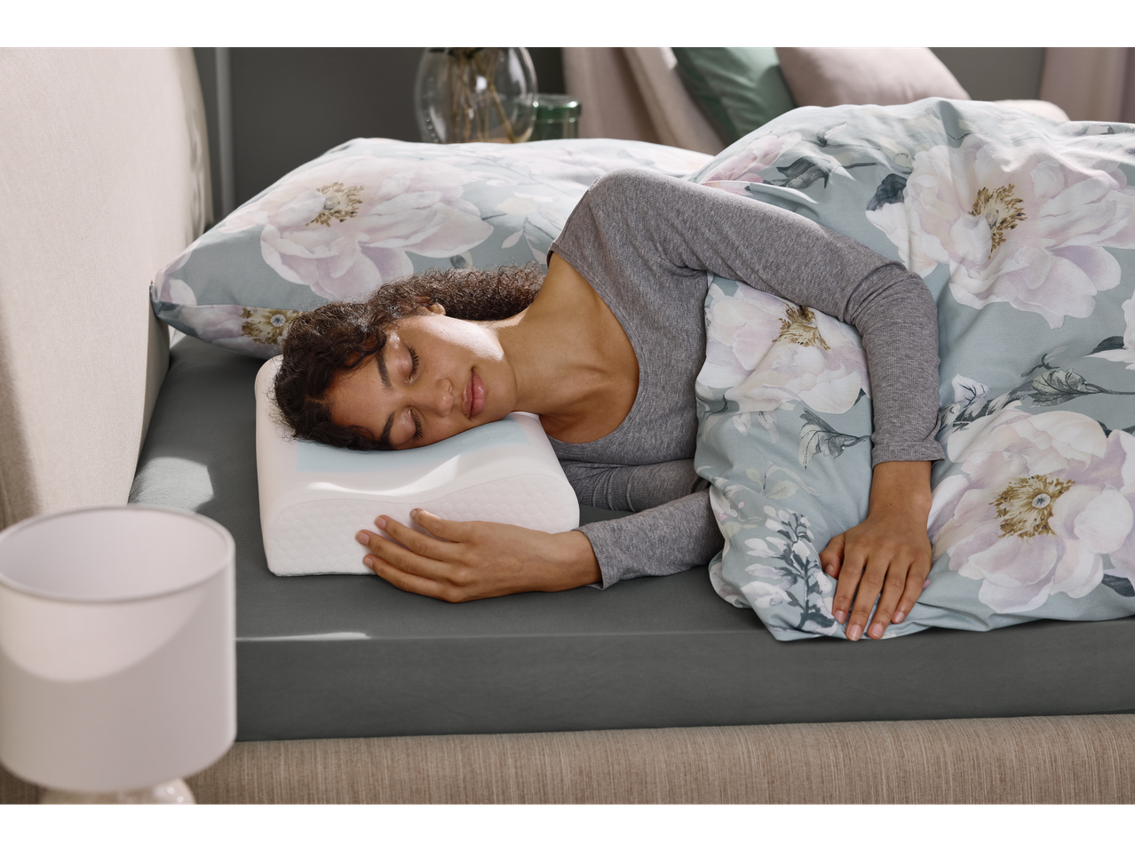 Žena spava na Livarno® anatomskom jastuku u krevetu s cvjetnom posteljinom.