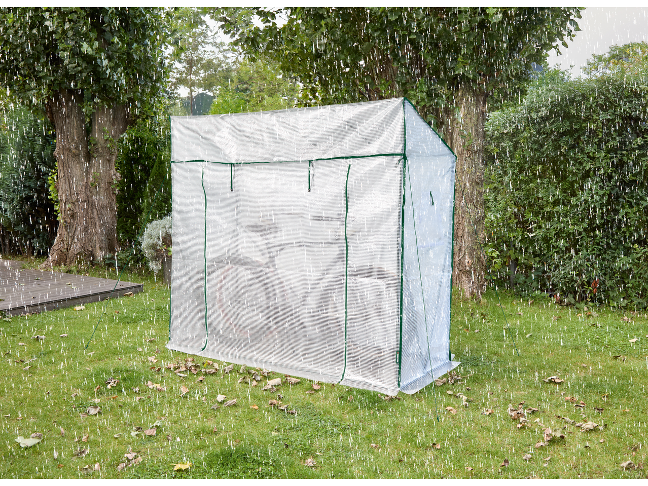 Greenhouse in a garden during rain, protecting plants from the elements.