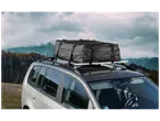 Sac de toit de voiture noir sur un porte-bagages, avec un paysage montagneux en arrière-plan.