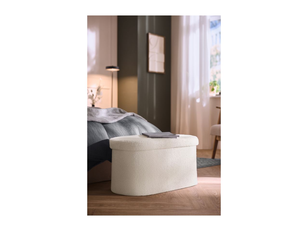 Cream bouclé ottoman in a bedroom with a bed and window.