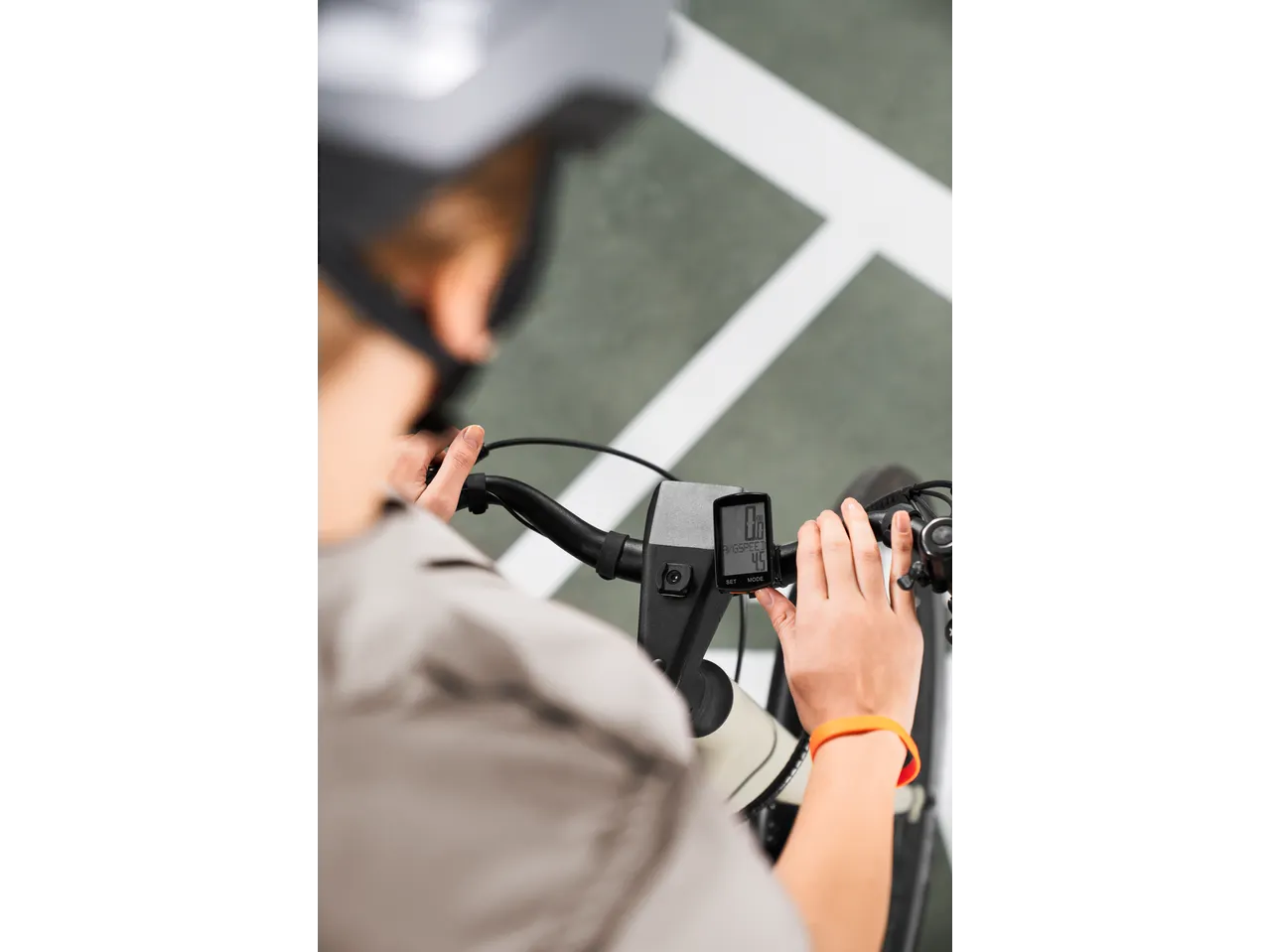 Ciclist cu cască ajustând ciclocomputerul, care afișează 0.0 km/h și 4.5 viteză medie.