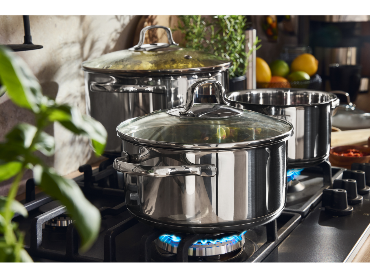 Oale din oțel inoxidabil cu capace de sticlă pe o plită modernă cu gaz în bucătărie.