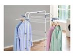 White clothes drying rack with blue and pink shirts hanging on it, next to a washing machine.