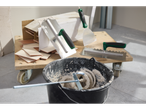 Tiling tools and materials, including trowels, spatulas, and a bucket of mixed mortar, on a wooden cart.