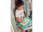 Djevojčica s majicom Peppa Pig crta na zelenoj ploči za crtanje.