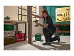 Man using a cordless drill to work on a wooden beam in a workshop setting.
