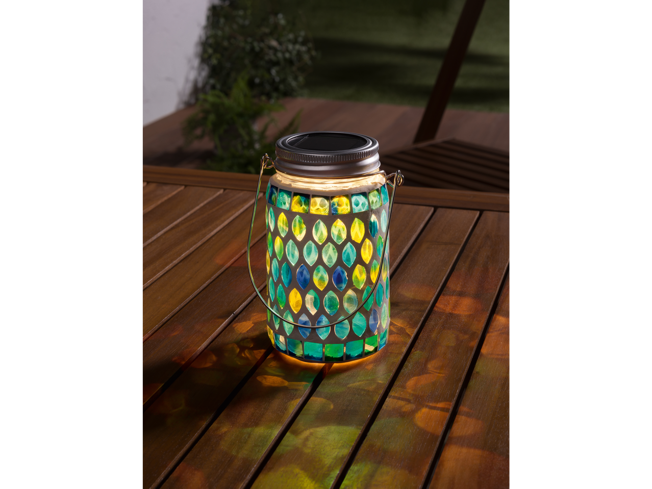 Luminária solar com design de mosaico em uma mesa.
