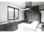 Cozinha moderna com bancada branca, ilha central e exaustor de aço inoxidável.