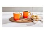 Two orange mugs of coffee, one with foam, on a wooden board with cookies and sugar.