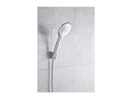 Chrome shower head and hose mounted on a light grey tiled wall.