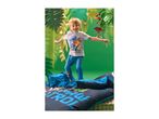 Boy in dinosaur-themed pajamas jumping on a bed with matching bedding, jungle background.