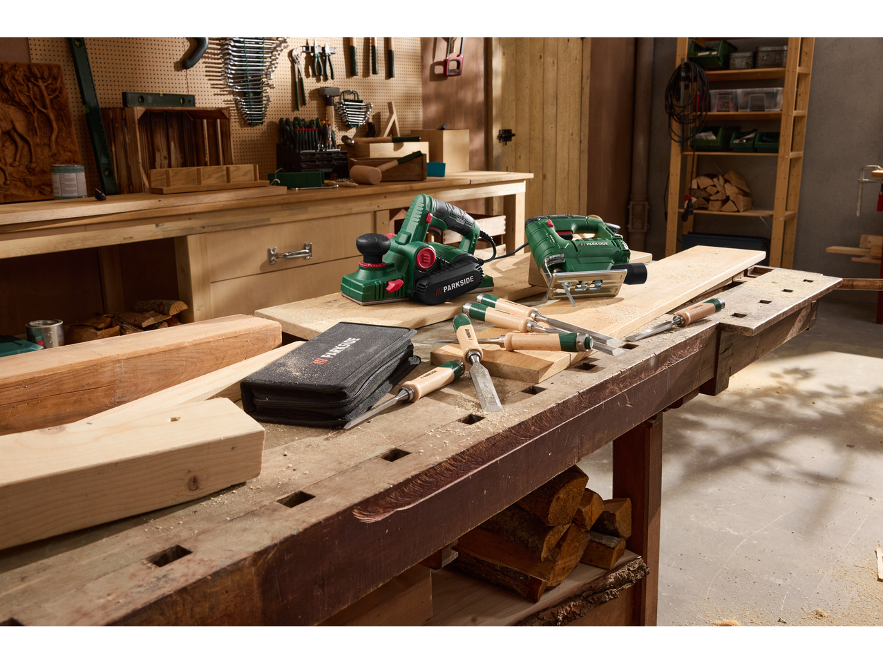 Electric planer and jigsaw on a workbench with chisels and wood in a workshop.