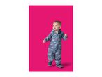 Toddler in a blue rain suit with vehicle patterns, standing on a pink background.