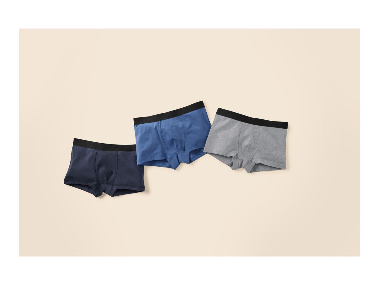 Three men's boxer briefs in navy, blue, and grey, with black waistbands, on a light background.