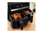 Dual air fryer with a whole roasted chicken and french fries, on a wooden surface.