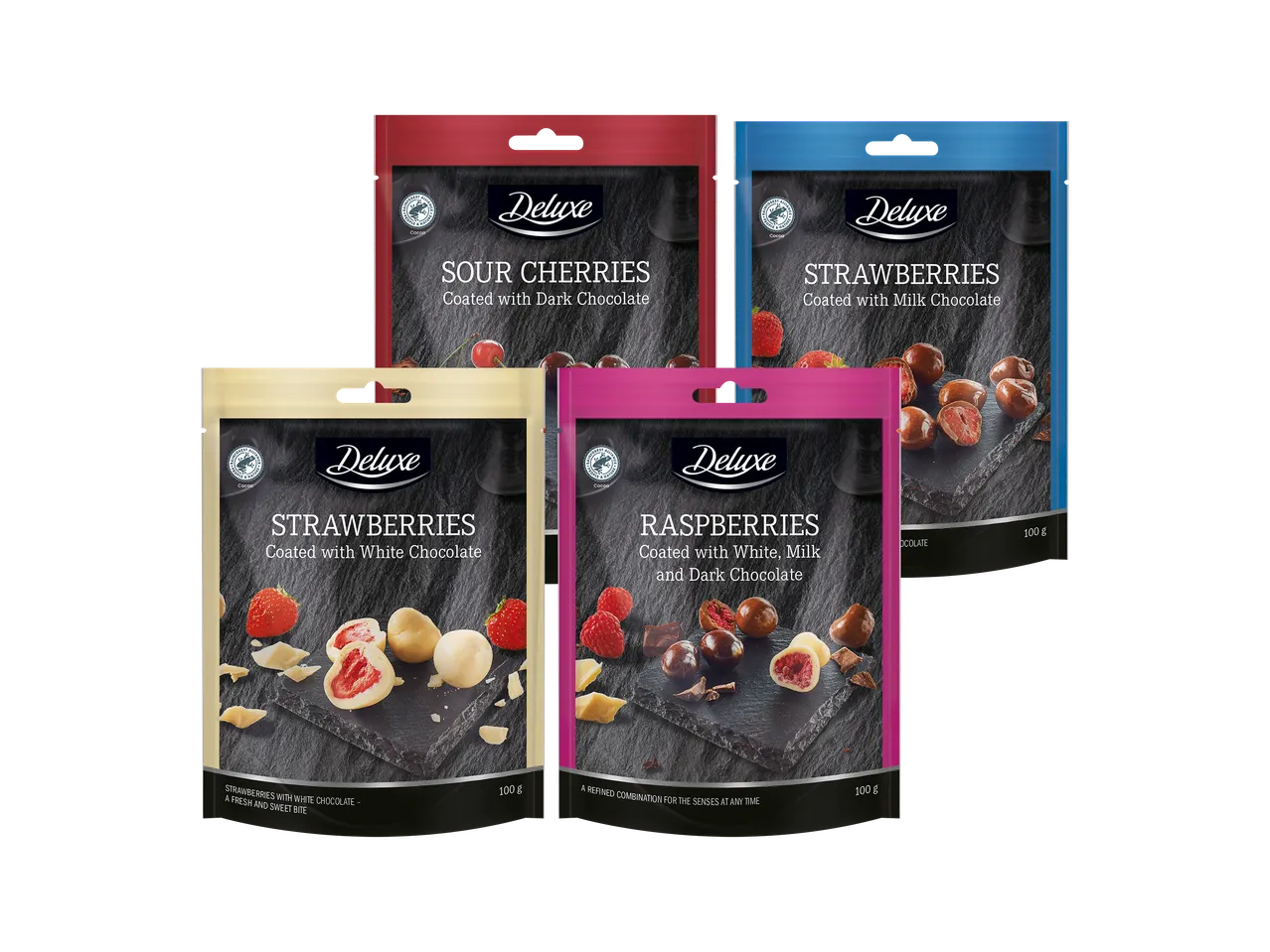 Neljä pussia suklaapäällysteisiä hedelmiä: hapankirsikoita, mansikoita ja vadelmia.