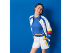 Mulher sorridente com roupa de esporte Lidl: shorts brancos e jaqueta azul.