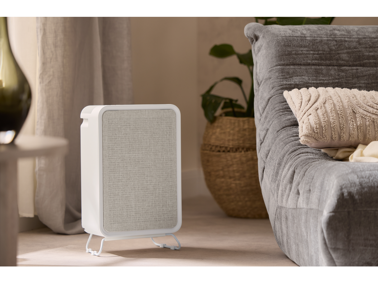 Purificator de aer LIVARNO lângă o canapea gri cu perne și o plantă.