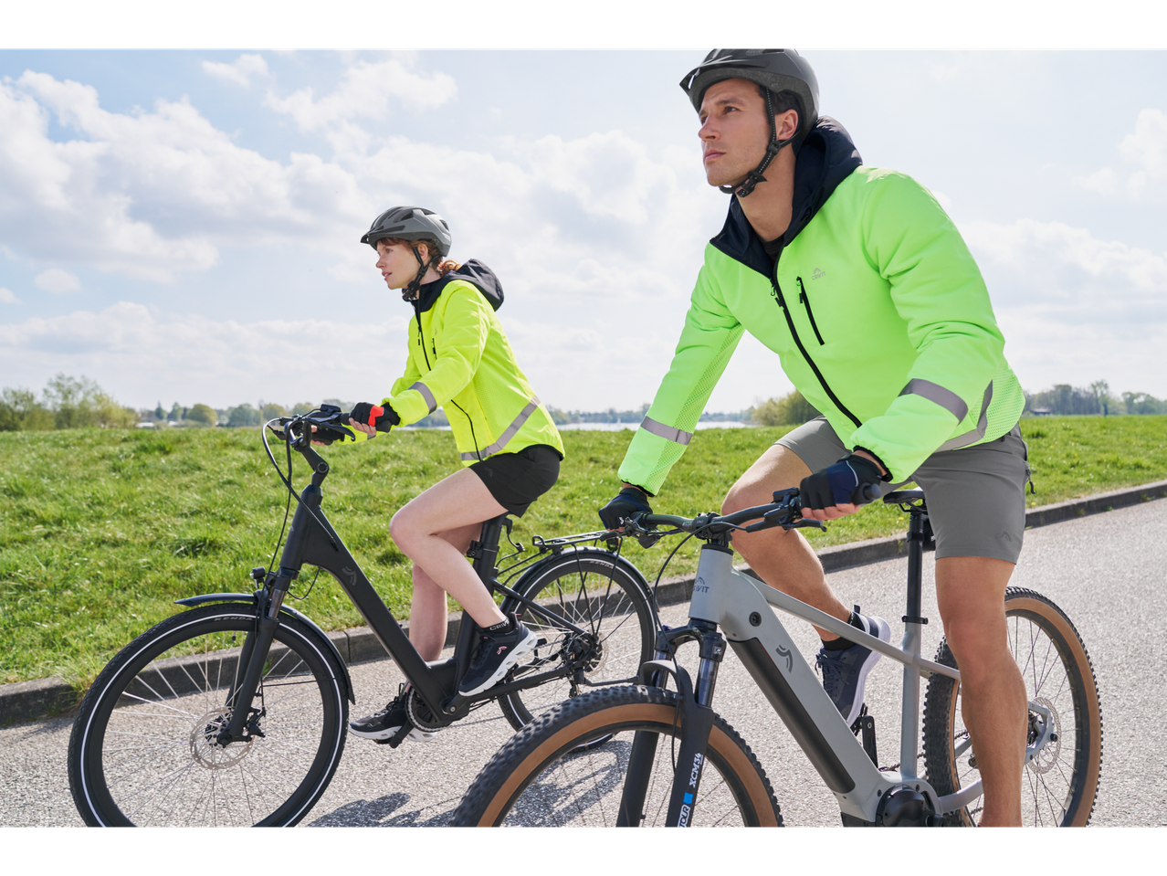 Cuplu care merge cu biciclete electrice, îmbrăcați în jachete Craft.
