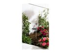 Solar-powered garden stake light with a glass globe, surrounded by pink flowers and green plants.