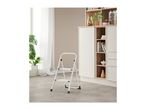 A white step stool on a tiled floor in a modern kitchen with open shelving.