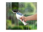 Hand holding a window cleaner, cleaning a steamy window with a green background.