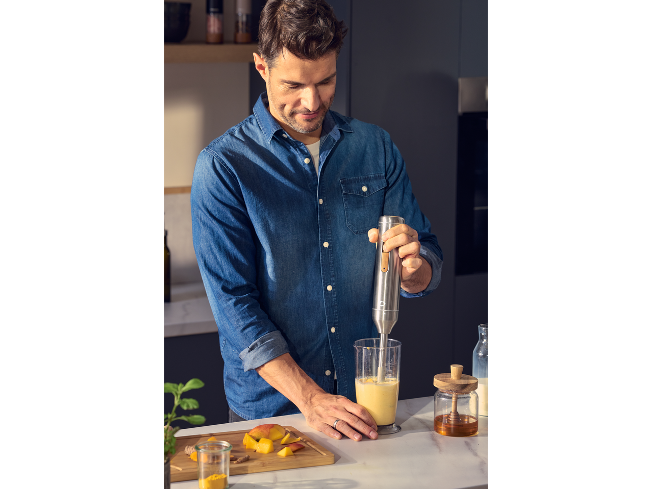 Man blending a mango smoothie with a SILVERCREST® 600W Hand Blender.