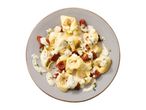 Tortellini with creamy sauce, sun-dried tomatoes, and herbs on a grey plate.
