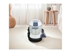 A compact carpet cleaner on a light rug in a modern living room.