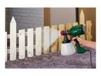 A person using a Parkside paint spray gun to paint a wooden fence white.