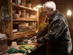Ένας άντρας χρησιμοποιεί κλαδευτήρι Parkside σε ένα ακατάστατο εργαστήριο κήπου.
