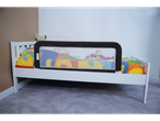 White toddler bed with a black Safety 1st bed rail and colorful bedding.