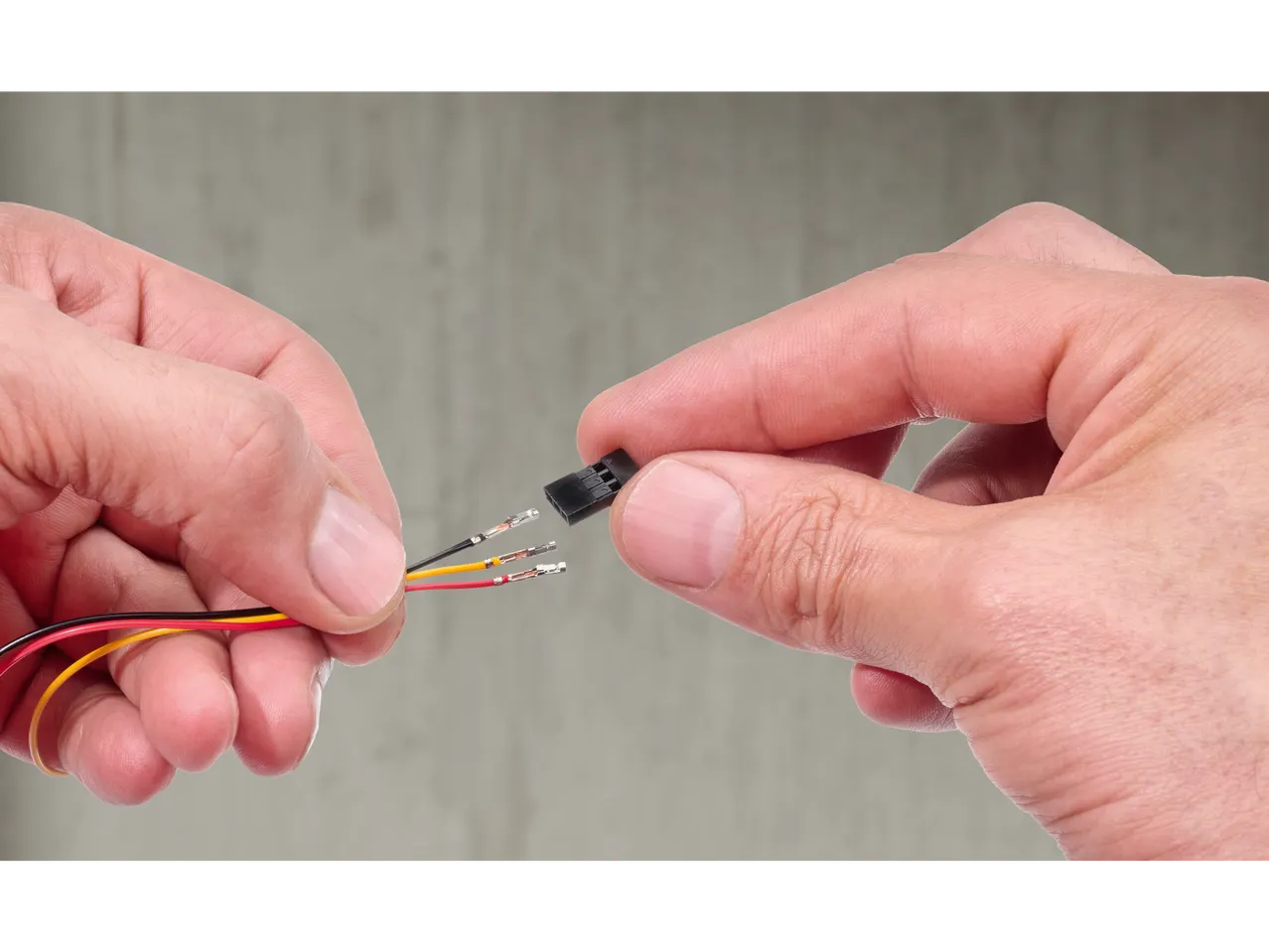 Mâini conectând trei fire la un conector negru.