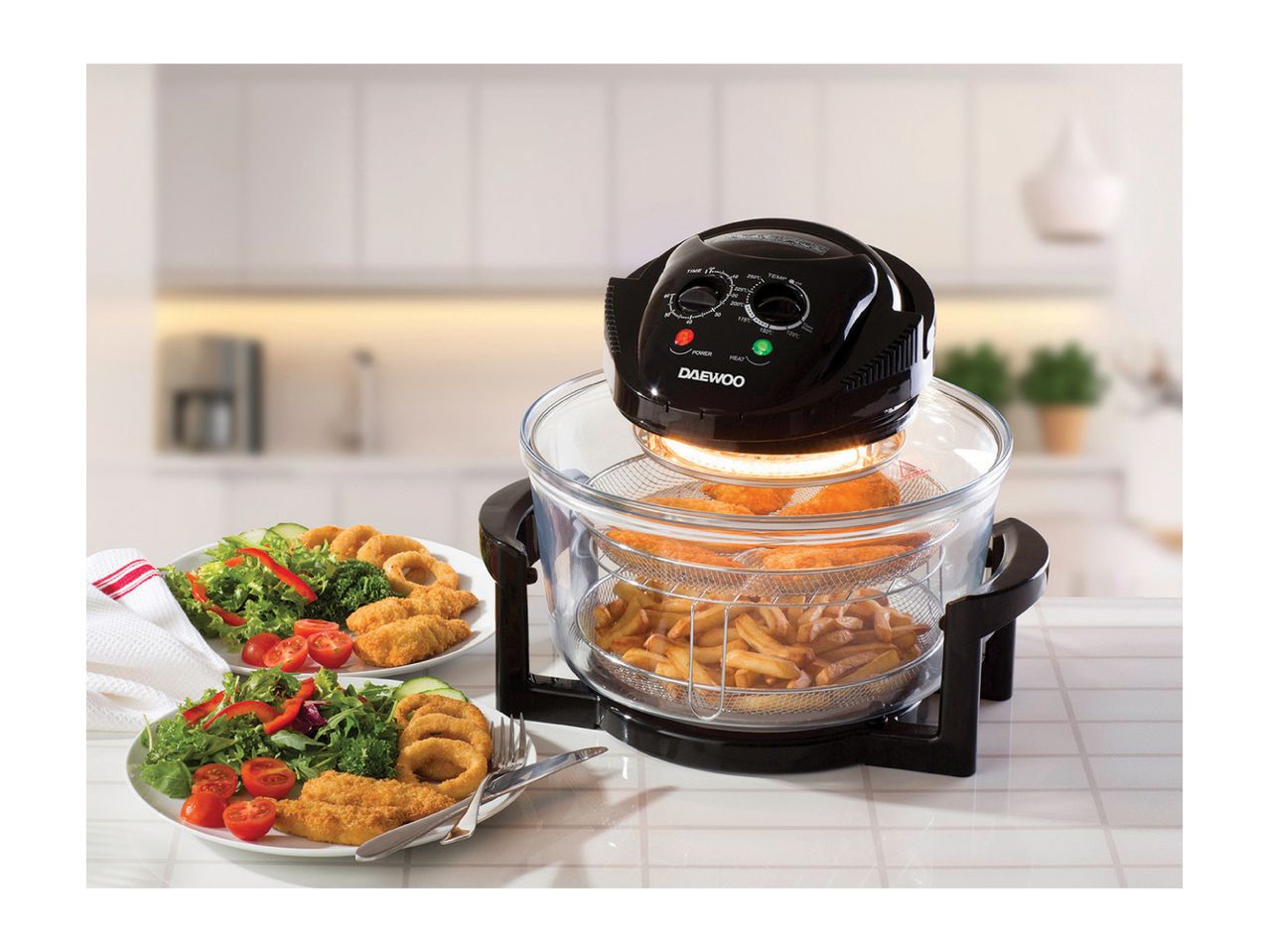 Daewoo air fryer with chicken nuggets, onion rings, fries, and salad on a kitchen counter.