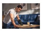Man cleaning crumbs from a wooden coffee table with a handheld vacuum cleaner.