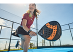 Mulher com roupa de padel e raquete de padel num campo azul.