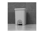 White woven pedal bin on a grey tiled floor with a reflection.