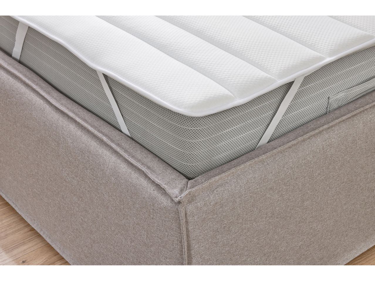 A mattress topper with elastic straps is shown on a bed.