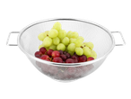 Une passoire en acier inoxydable avec des raisins verts et rouges.