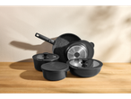 Juodas Silvercrest® puodų ir keptuvių rinkinys su dangčiais ant medinio stalo.