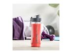 A red smoothie in a clear bottle with a dark grey lid, surrounded by gym equipment.