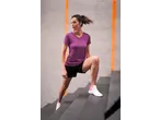 Mulher com t-shirt e calções CRIVIT, a subir escadas com sapatilhas CRIVIT.