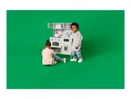 Two children playing with a toy kitchen set, one standing and one sitting.