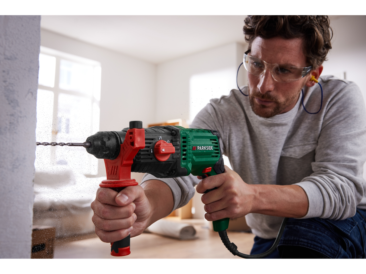 A man uses a Parkside SDS-Plus Hammer Drill to drill a hole in a wall.
